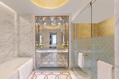 a bathroom with a tub and a shower with a mirror at The Ritz-Carlton Rabat, Dar Es Salam in Rabat