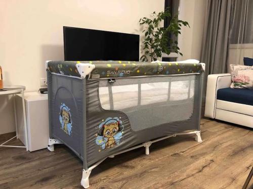 ein Kinderbett im Wohnzimmer mit Fernseher in der Unterkunft HOT Main Square Newly Built Modern Apartment in Burgas City