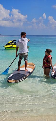 a man standing on a paddle board in the ocean at Chambao Maldives in Guraidhoo