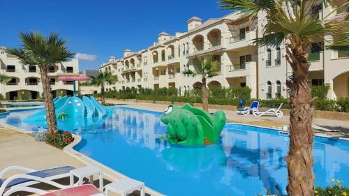 a pool at the resort with a slide and palm trees at Lasirina palm beach for families only in Ain Sokhna