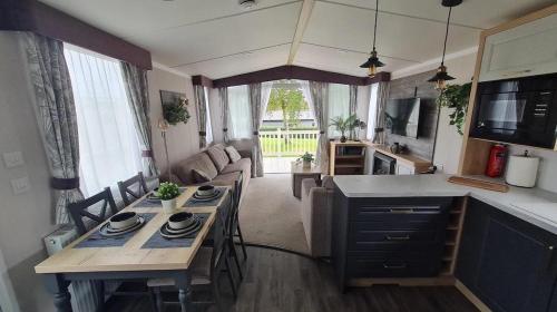 a kitchen and living room with a table and a couch at STYLISH MODERN CONTEMPORARY PET FREE HOLIDAY HOME ON AWARD WINNING SHOREFIELD COUNTRY PARK Edge New Forest ENTERTAINMENT AND LEISURE PASSES INCLUDED in Milford on Sea