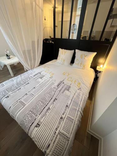 - un lit avec une couette et des oreillers blancs dans l'établissement Grand studio 1er étage au calme centre ville proximité Cathédrale, à Orléans