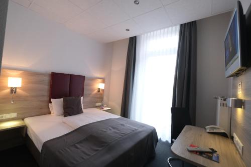 a hotel room with a bed and a window at Hotel Hohenstaufen in Koblenz