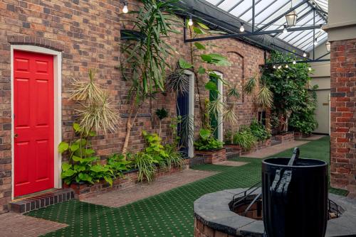 a brick building with a red door and some plants at Best Western Valley Hotel in Ironbridge