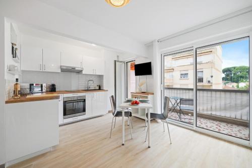 una cocina con electrodomésticos blancos y una mesa con sillas. en Le Mistral, en Niza
