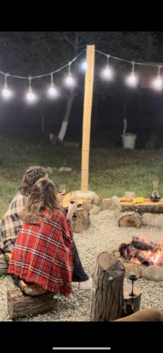 a woman sitting on a bench in front of a fire at მშვიდი-Mshvidi in Sagarejo