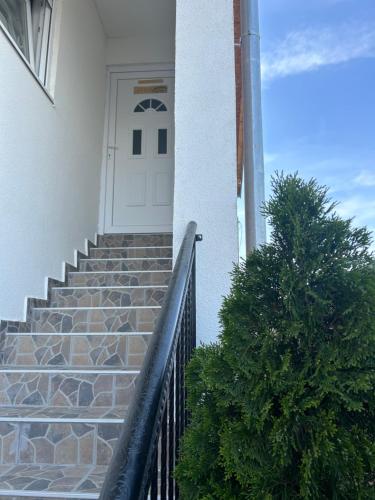a white door on a white house with stairs at Apartman Gold LUX in Surčin