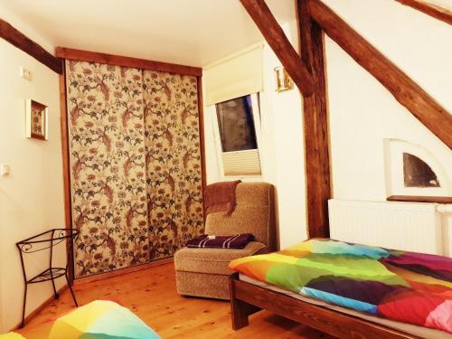 a bedroom with a bed and a chair and a window at Dom Gościnny Hansel & Gretel in Kallinowen