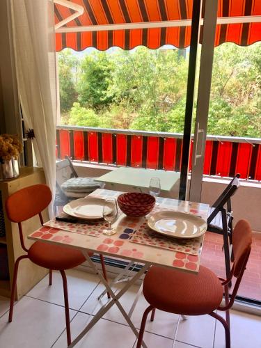 - une table avec deux chaises et une table avec des assiettes dans l'établissement Grand studio à Hyères entre mer et ville, à Hyères