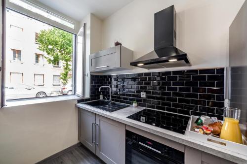 une cuisine avec un évier et une fenêtre dans l'établissement Escapade urbaine- Monchat- Lyon, à Lyon