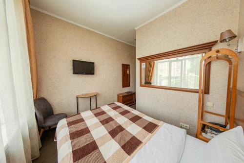 a bedroom with a bed and a tv on the wall at Ajour in Almaty