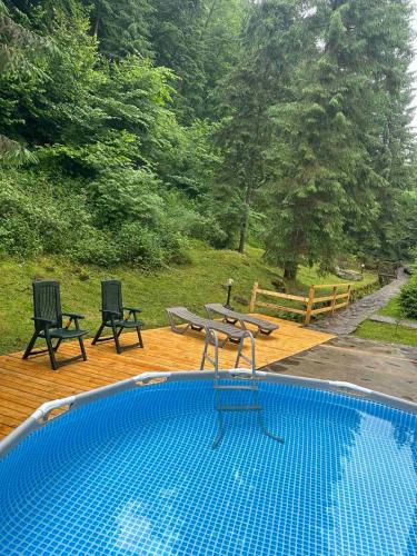 a swimming pool with two chairs and a table at Hotel Dykyi Med in Tatariv