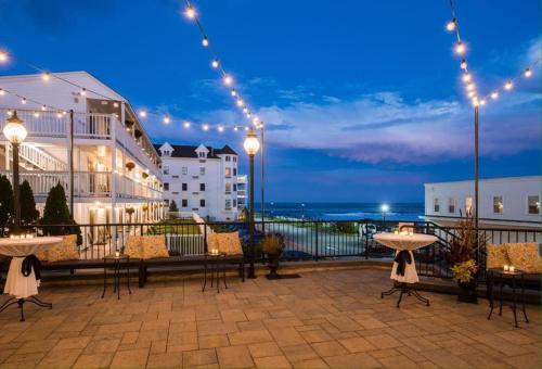 a patio with tables and chairs and a view of the ocean at Union Bluff Hotel in York Beach