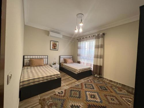 a bedroom with two beds and a window at La Vista Bay North Coast Halafawy's Full Sea View لا فيستا باي الساحل الشمالي بيت الحلفاوي in Dawwār Ḩājj as Sayyid Rizq