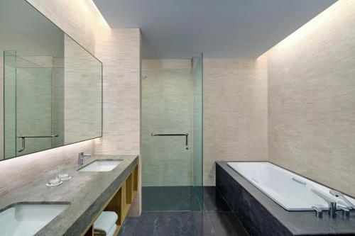 a bathroom with two sinks and a glass shower at Aloft South Jakarta in Jakarta
