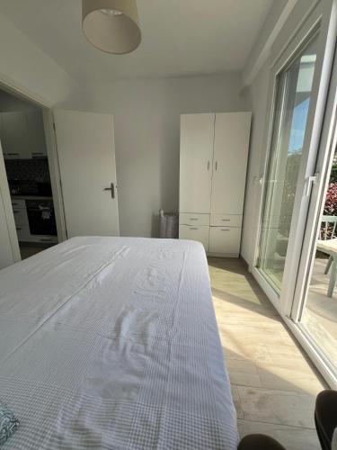 a white bedroom with a bed and a large window at Perla 2 Paralia Ofriniou in Ofrínion
