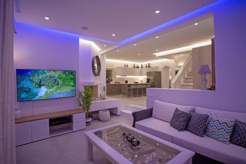 a living room with a couch and a tv at VILLA PANAMERA Mykonos, Private Heaven, Supreme View! in Fanari