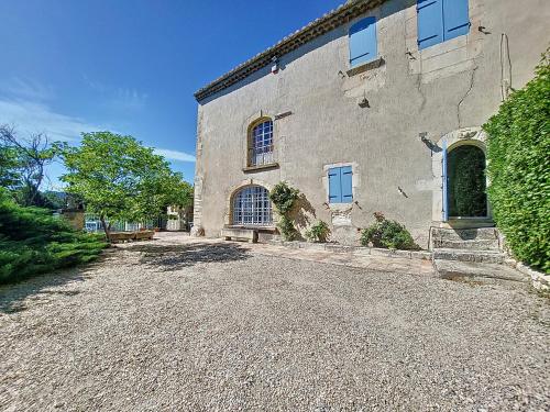 Un grand bâtiment avec une allée en gravier se trouve en face de l'établissement. dans l'établissement MAS provencal piscine, aux Baux-de-Provence