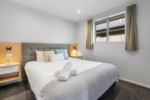 a bedroom with a large white bed with a window at Tasman Holiday Parks - Te Anau in Te Anau