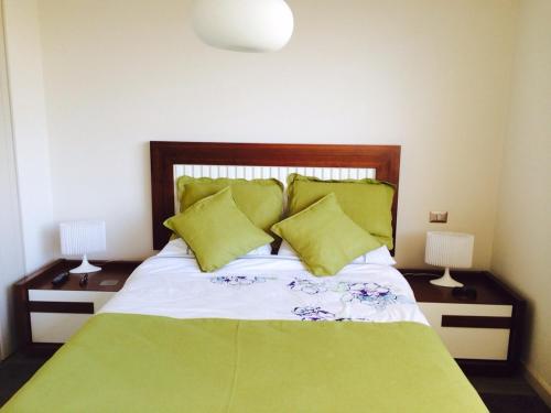 a bedroom with a bed with green sheets and pillows at Reñaca Park Apartment in Viña del Mar