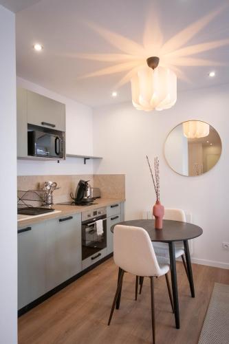 une cuisine avec une table et des chaises ainsi qu'un lustre dans l'établissement Bibemus Casa Maja - baignoire balnéo - parking - terrasse, à Saint-Étienne
