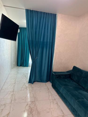 a living room with a couch and blue curtains at Arcadia Adelina in Odesa