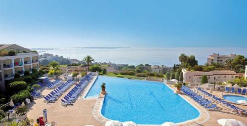 une grande piscine avec des chaises longues et l'océan dans l'établissement Appartement haut de gamme vue mer classé 3 étoiles, à Cannes