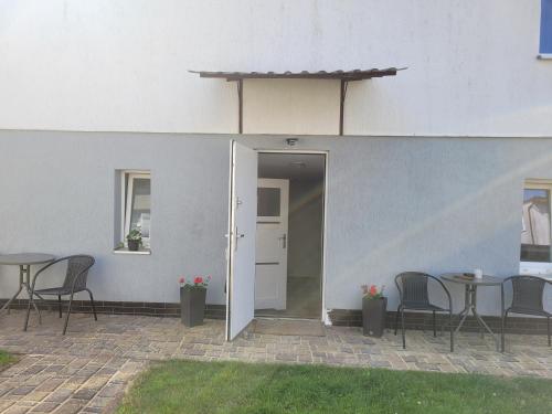 a patio with tables and chairs and a white building at Pokoje Gościnne Galeon w Darłówku in Darłowo