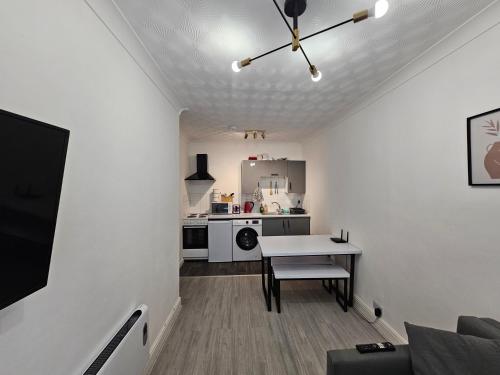 a living room with a table and a kitchen at Modern & Stylish 1 bedroom flat in Bridgend town in Bridgend
