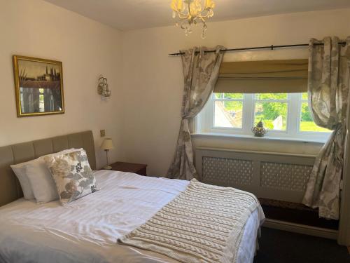 een slaapkamer met een bed met een raam en een kroonluchter bij Lulus in St Bees