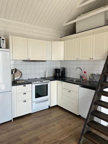 a kitchen with white appliances and a wooden floor at Sjöstugan in Mariestad