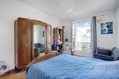 une chambre avec un lit bleu et une grande fenêtre dans l'établissement Appartement familial avec vue - République, à Paris