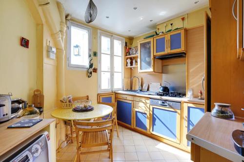 une cuisine avec des armoires bleues et une petite table dans l'établissement Appartement familial avec vue - République, à Paris