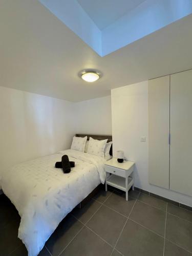 ein Schlafzimmer mit einem weißen Bett mit einer schwarzen Tasche darauf in der Unterkunft Appartement moderne avec Balcon proche de Paris in Aubervilliers