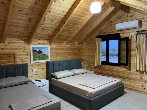 1 dormitorio con 2 camas en una cabaña de madera en Beni Rooms Tale en Lezhë