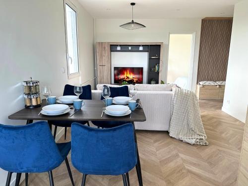 un salon avec une table et des chaises bleues dans l'établissement Appartement vue panoramique Antony, 8mn RER B et C, à Antony