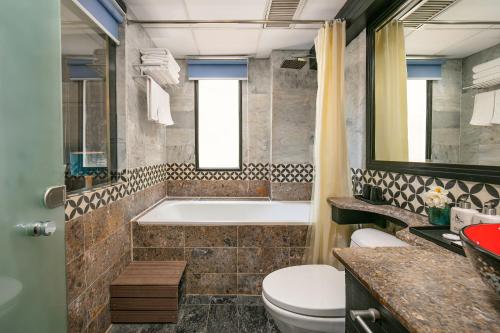 a bathroom with a tub and a toilet and a sink at Ja Cosmo Hotel and Spa in Hanoi