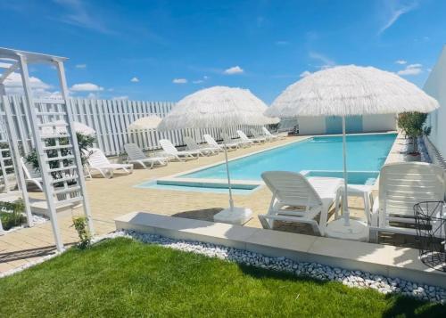 a pool with chairs and umbrellas on a patio at Alma Rezidence in Turda