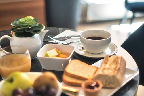 a table with a plate of food and a cup of coffee at Kyriad Prestige Mulhouse - Basel in Sausheim