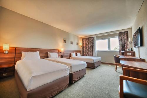 a hotel room with two beds and a desk at Kyriad Prestige Mulhouse - Basel in Sausheim