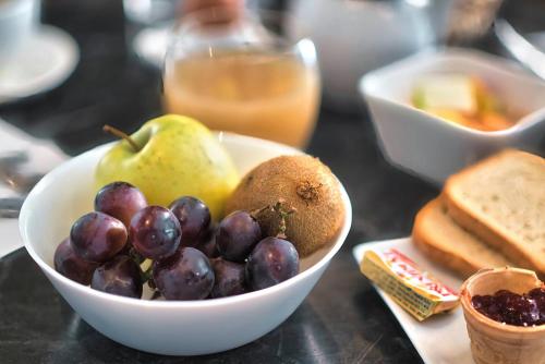 a bowl of fruit on a table with a plate of bread at Kyriad Prestige Mulhouse - Basel in Sausheim