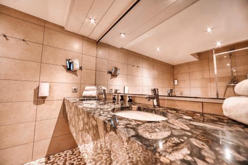 a bathroom with a sink and a mirror at Kyriad Prestige Mulhouse - Basel in Sausheim
