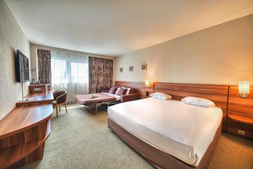 a hotel room with a bed and a couch at Kyriad Prestige Mulhouse - Basel in Sausheim