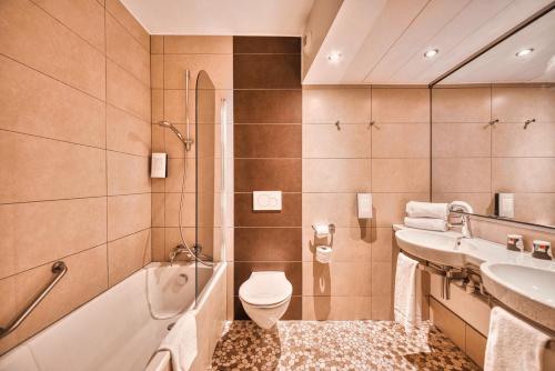 a bathroom with a toilet and a tub and a sink at Kyriad Prestige Mulhouse - Basel in Sausheim