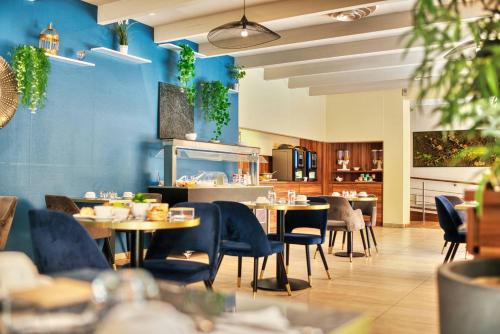 a restaurant with blue walls and tables and chairs at Kyriad Prestige Mulhouse - Basel in Sausheim