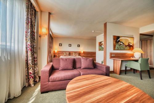 a living room with a purple couch and a table at Kyriad Prestige Mulhouse - Basel in Sausheim