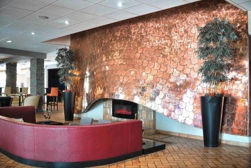 a brick wall with a fireplace in a lobby at Kyriad Prestige Mulhouse - Basel in Sausheim