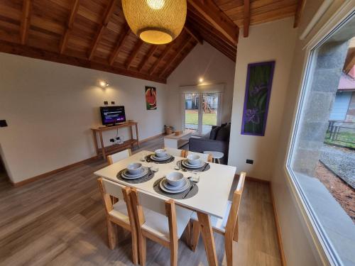 a dining room with a white table and chairs at Del Lacar - Andarlibre in San Martín de los Andes