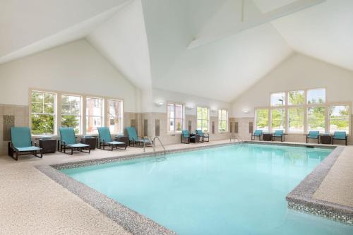 a large swimming pool with blue chairs and windows at Residence Inn Concord in Concord