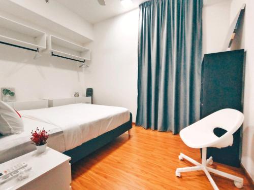 a bedroom with a bed and a white chair at Beacon Executive Suites - By IZ in George Town